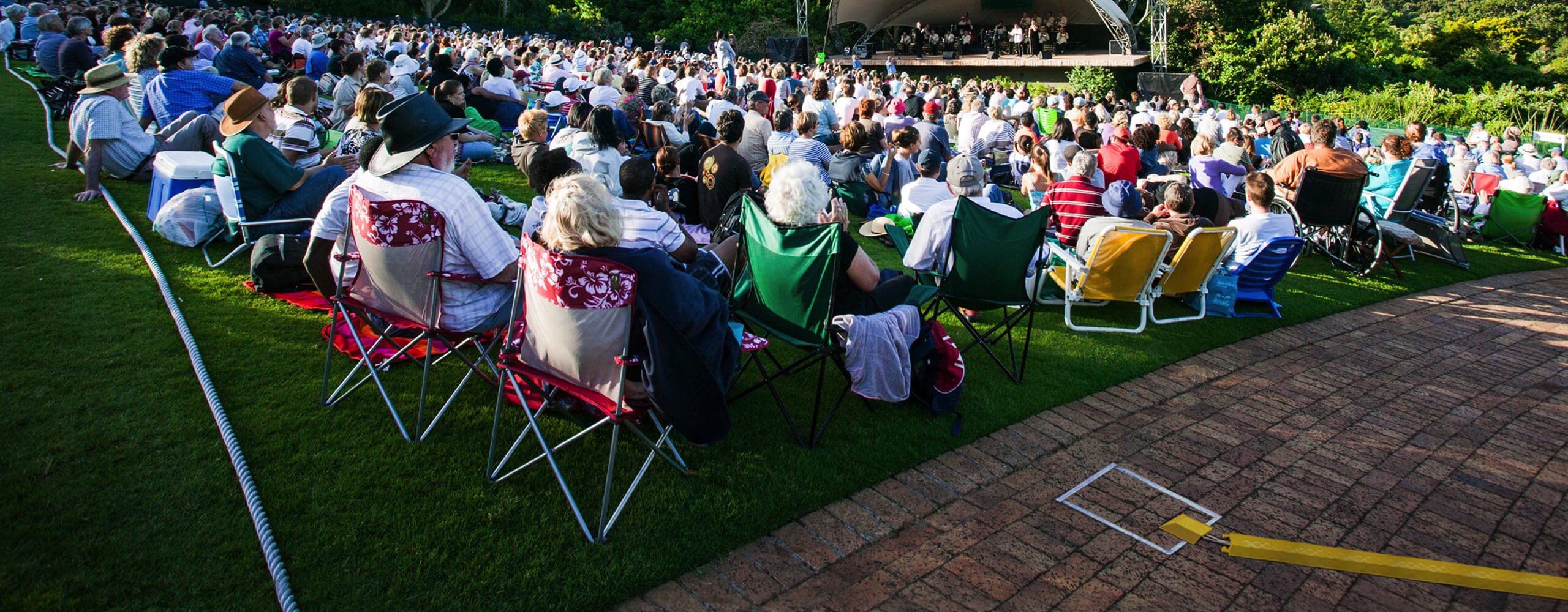 Image showing large seated crowd in front of an outdoor stage with closed in-ground unit in foreground.
